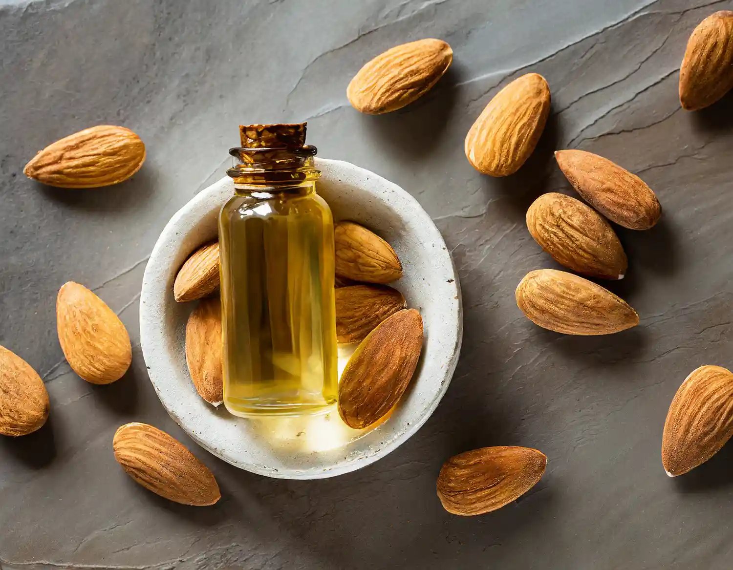 نمای نزدیک از روغن بادام شیرین خالص در بطری شیشه‌ای با بادام کامل طبیعی – مناسب برای مراقبت از پوست و مو، نرم‌کننده و تغذیه‌کننده طبیعی